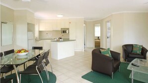 A modern apartment with a dining area, kitchen, and living space. - Town Beach Beachcomber Resort (Port Macquarie)
