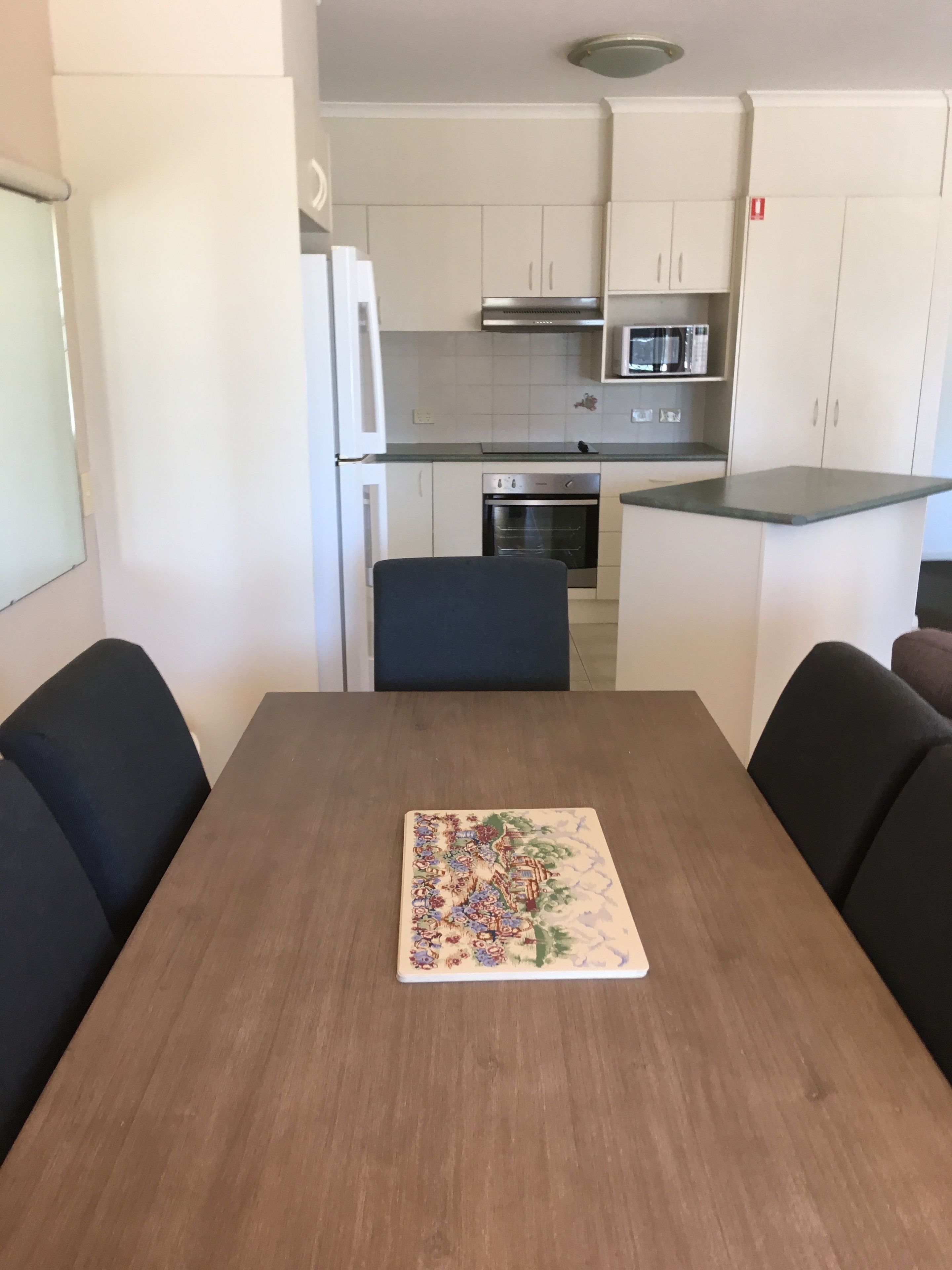 A modern kitchen with white cabinets, a stainless steel oven, and a microwave.