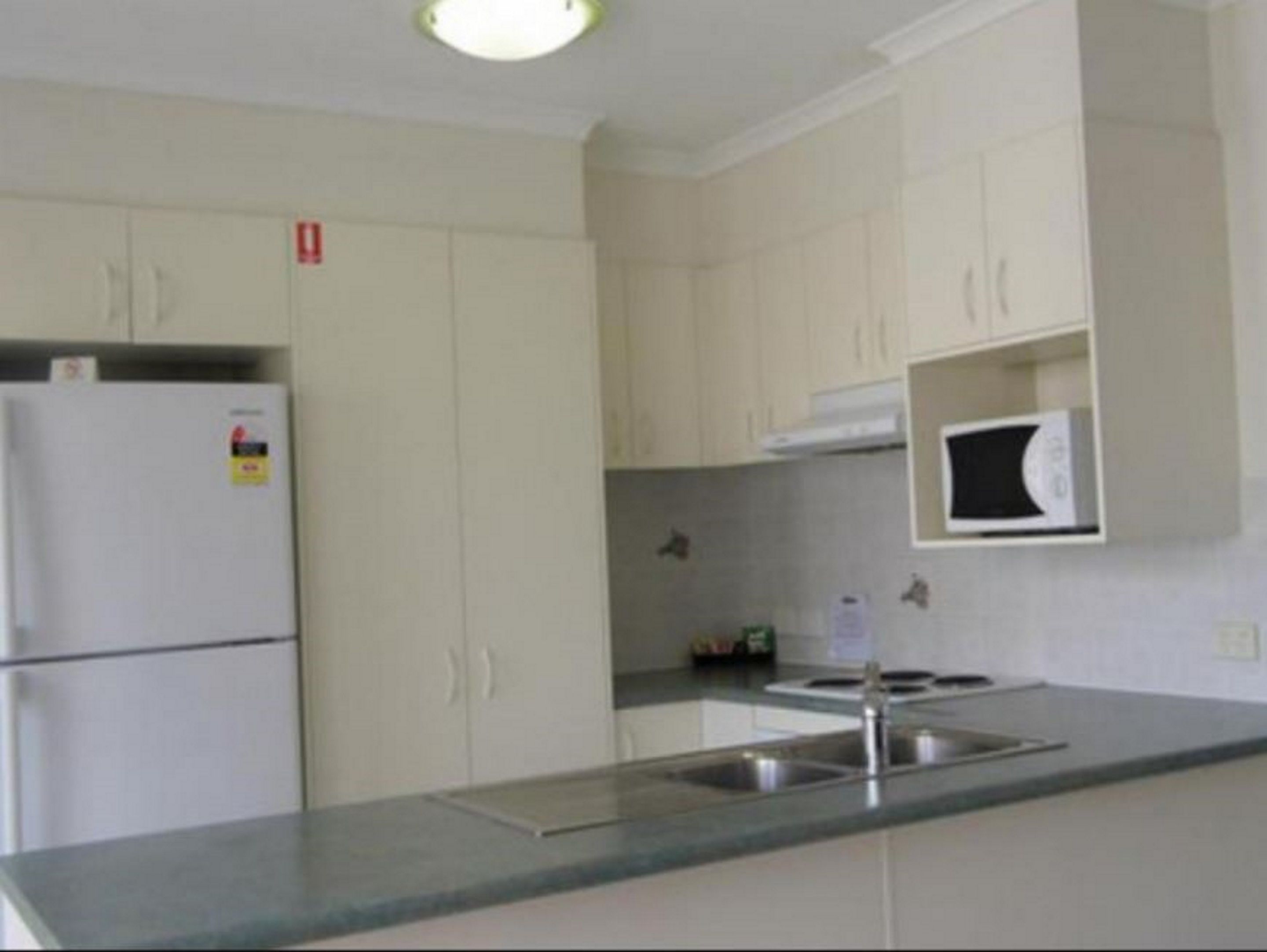 A kitchen with white cabinets, a built-in microwave, and a stainless steel sink.