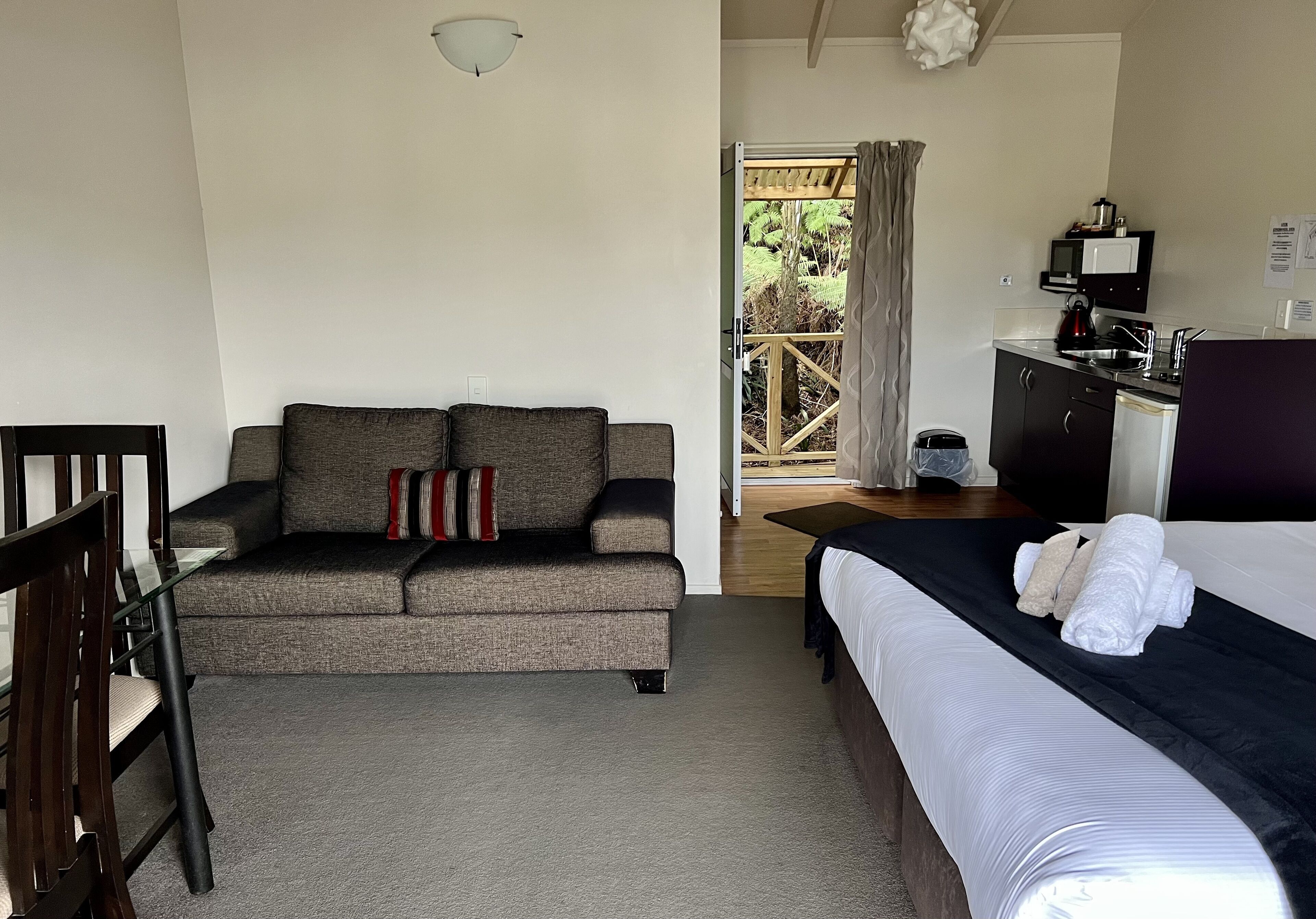 A hotel room with a sofa, a bed, a desk, and a view of the outdoors.