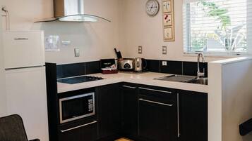 A compact kitchen with a microwave, stove, and sink.