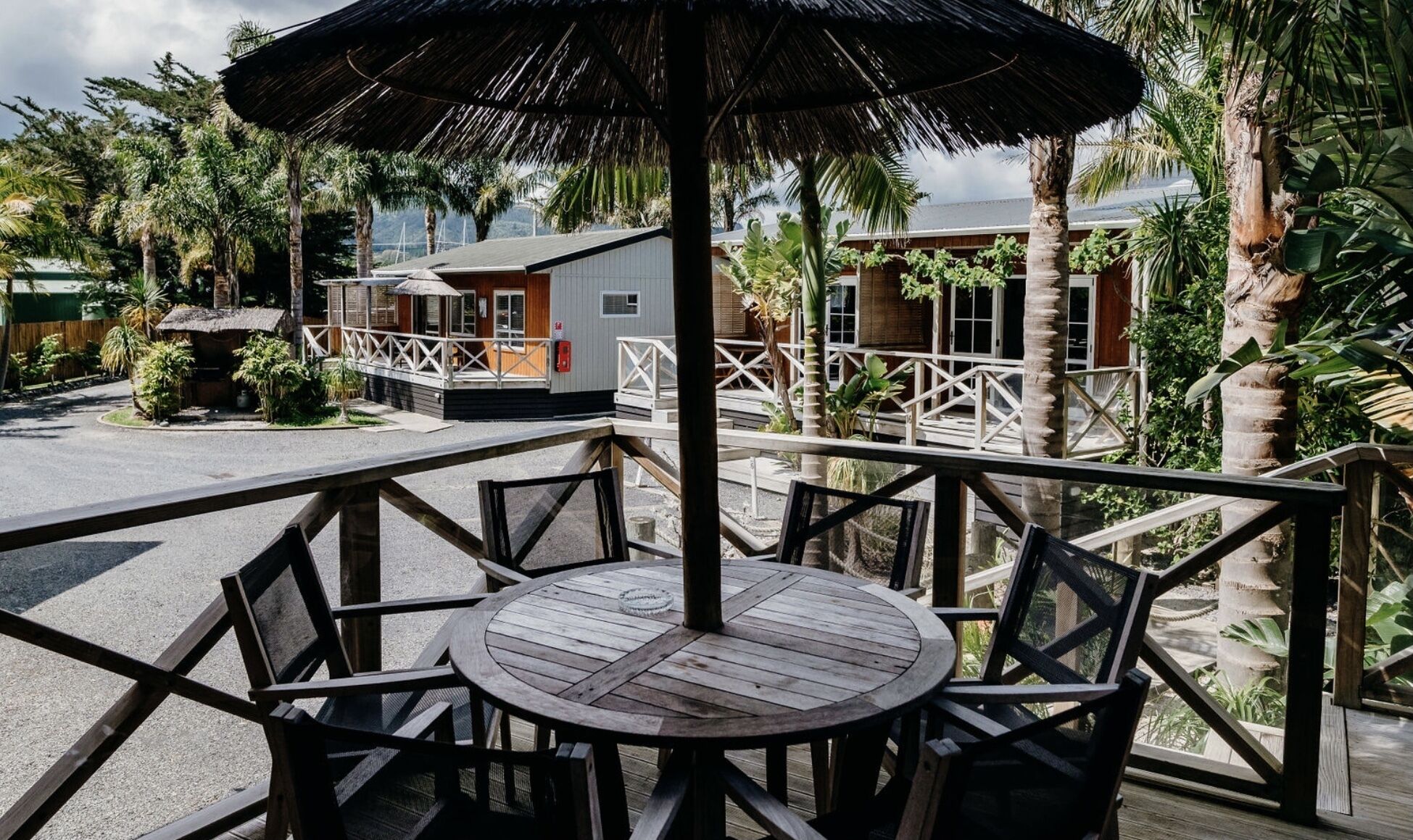 Eine Holzterrasse mit einem runden Tisch und Stühlen, umgeben von einem Geländer.