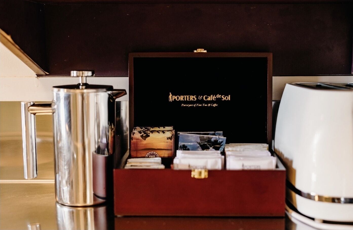 A coffee maker, a box with a coffee-themed design, and a coffee pot on a countertop.