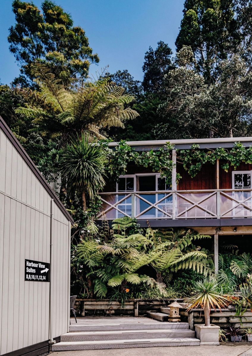 A building with a sign for 'Harbour View Suites' and a covered walkway with a view of the surrounding greenery.
