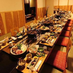 A long dining table with multiple dishes and a variety of utensils. - Motokawarayu (Okura)