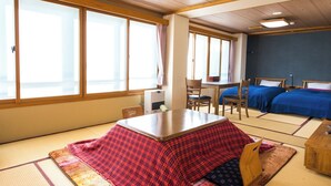 A traditional Japanese room with tatami flooring, a futon bed, a low table, and sliding doors. - Motokawarayu (Okura)