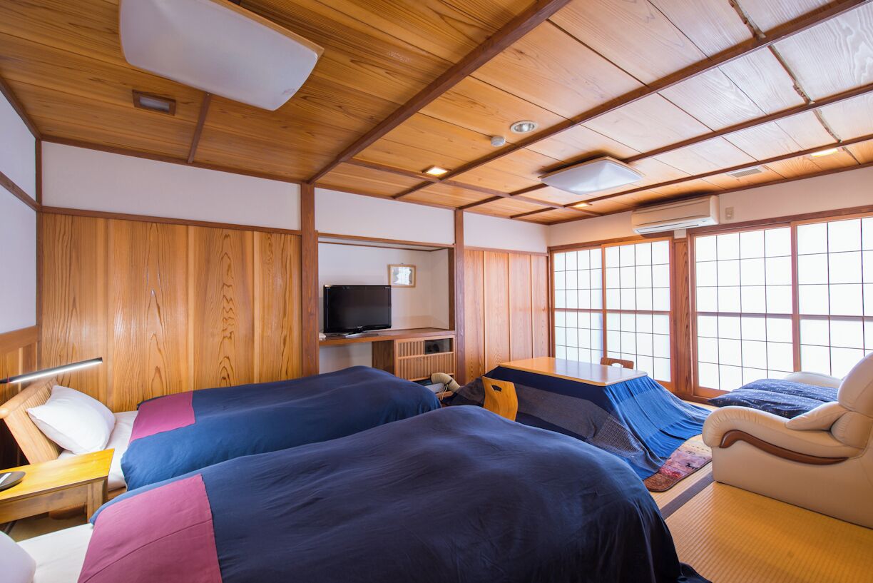 A room with two beds, a television, and a large window.