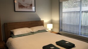 Un lit bien fait, avec des oreillers, une lampe de chevet et deux serviettes pliées posées sur le lit.