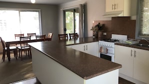 Une cuisine moderne dotée d’un îlot central, de meubles blancs et d’une cuisinière à gaz.