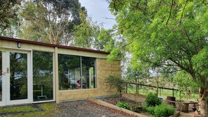 A modern building with large glass windows, a stone exterior, and a gravel driveway. - Neerim Country Cottages (Neerim South)