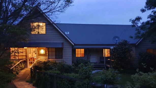 A two-story house with a porch, a visible staircase, and a pathway leading to the entrance. - Neerim Country Cottages (Neerim South)