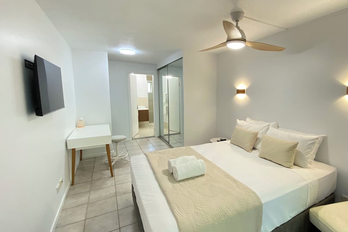 A hotel room with a bed, bedside table, and a ceiling fan.