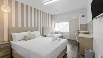 A hotel room with a large bed, a desk, and a TV.