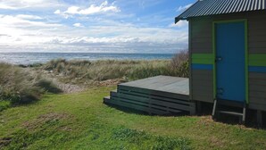 Un edificio frente al mar con una puerta azul, ubicado en un área ajardinada con vista al océano.