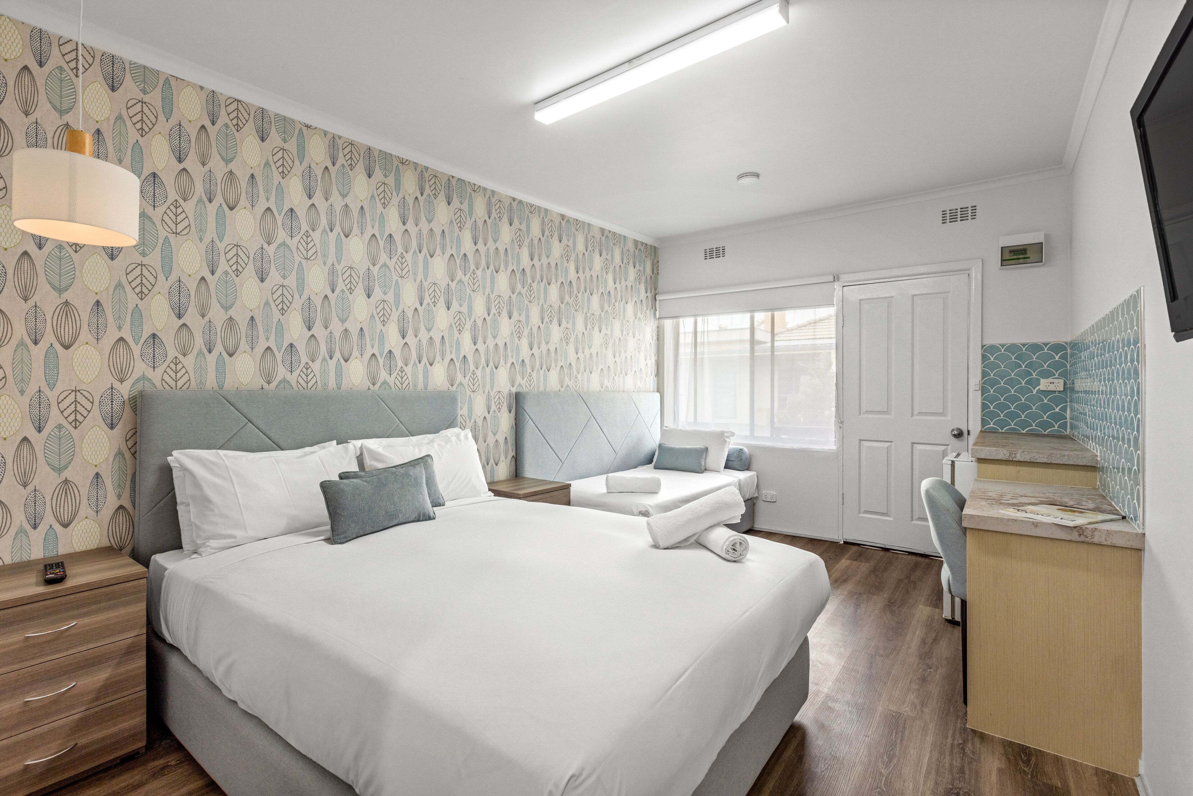 A hotel room with a large bed, a bedside table, a desk, and a window.