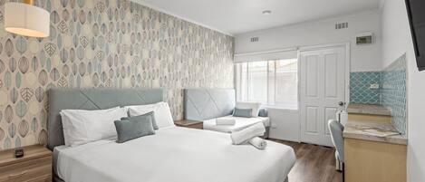 A hotel room with a large bed, a bedside table, a desk, and a window.