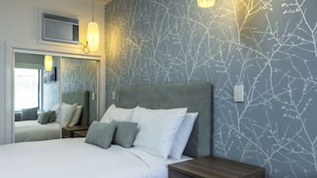 Une chambre à coucher comprenant un lit, des tables de chevet, un miroir et des lampes fixées au mur.