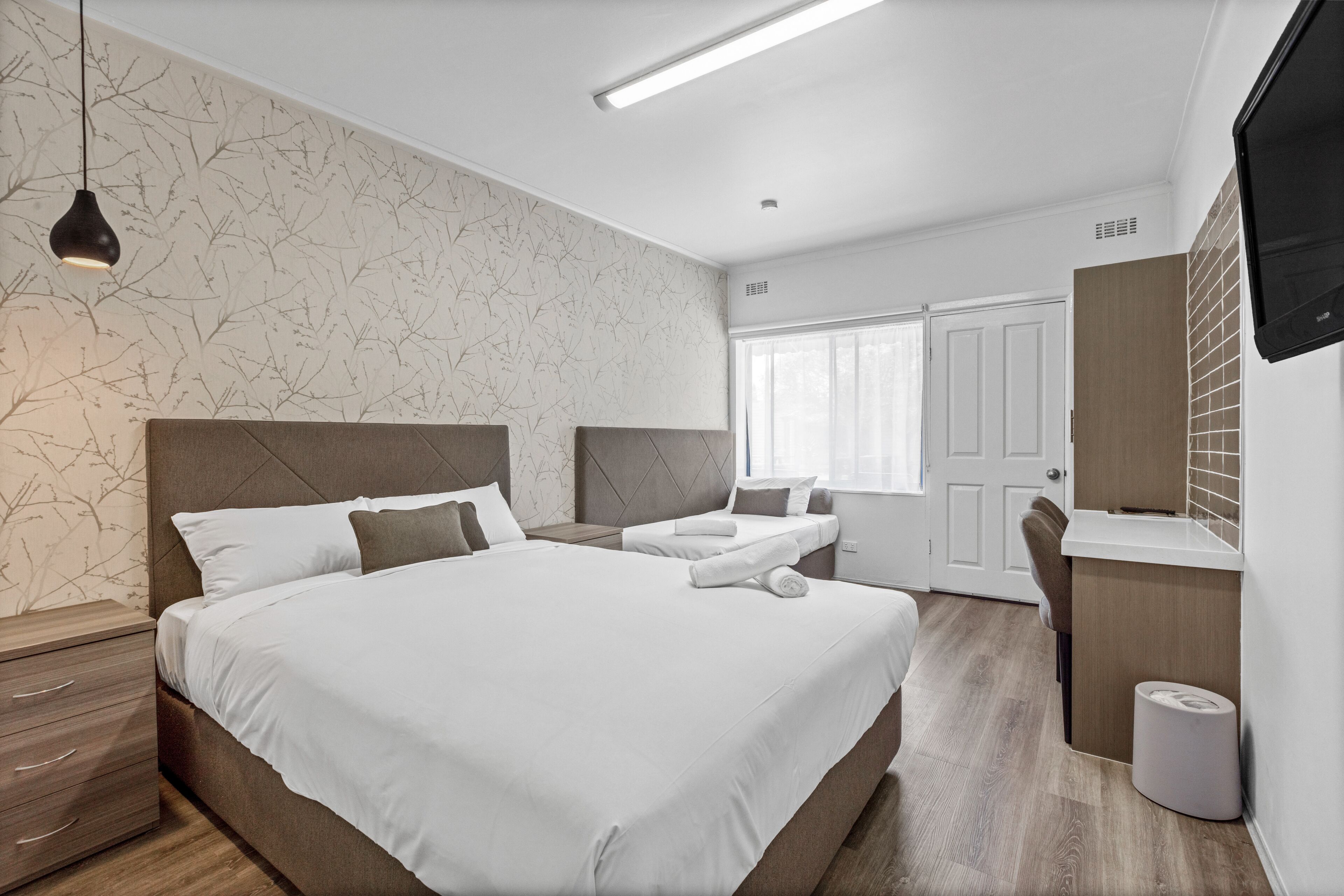 Habitación de hotel moderna con una cama grande, un escritorio y un televisor.