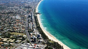 An aerial view of a coastal city with a long beachfront, dense urban area, and a clear blue ocean. - Pacific Regis Apartments (Burleigh Heads)