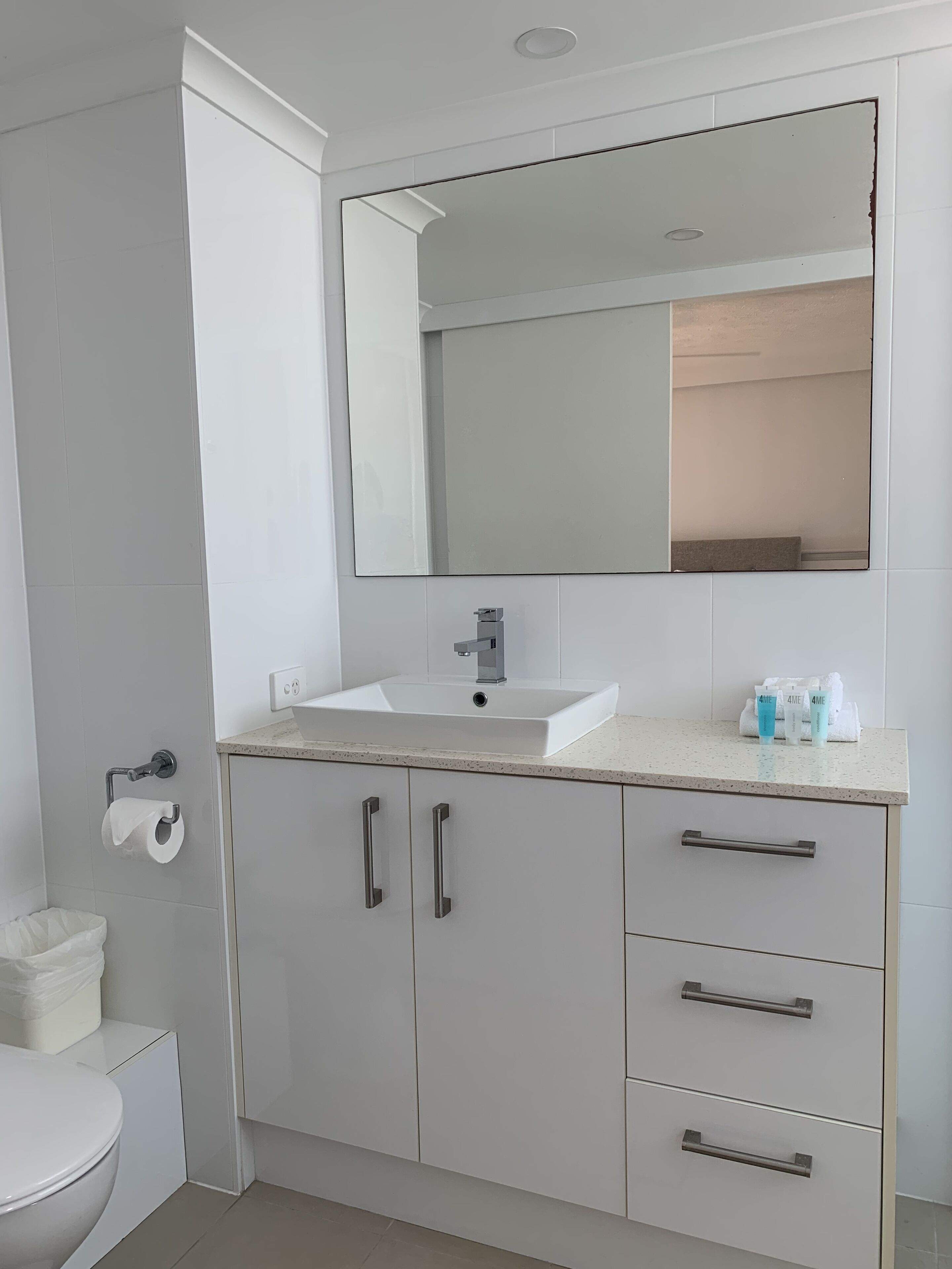 A bathroom with a white sink, a mirror, and a toilet.