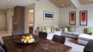A modern living room with a dining table, sofa, and framed artwork on the wall. - Altitude Apartments (Falls Creek)