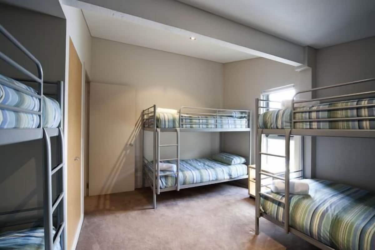 A room with bunk beds, a staircase, and a window.