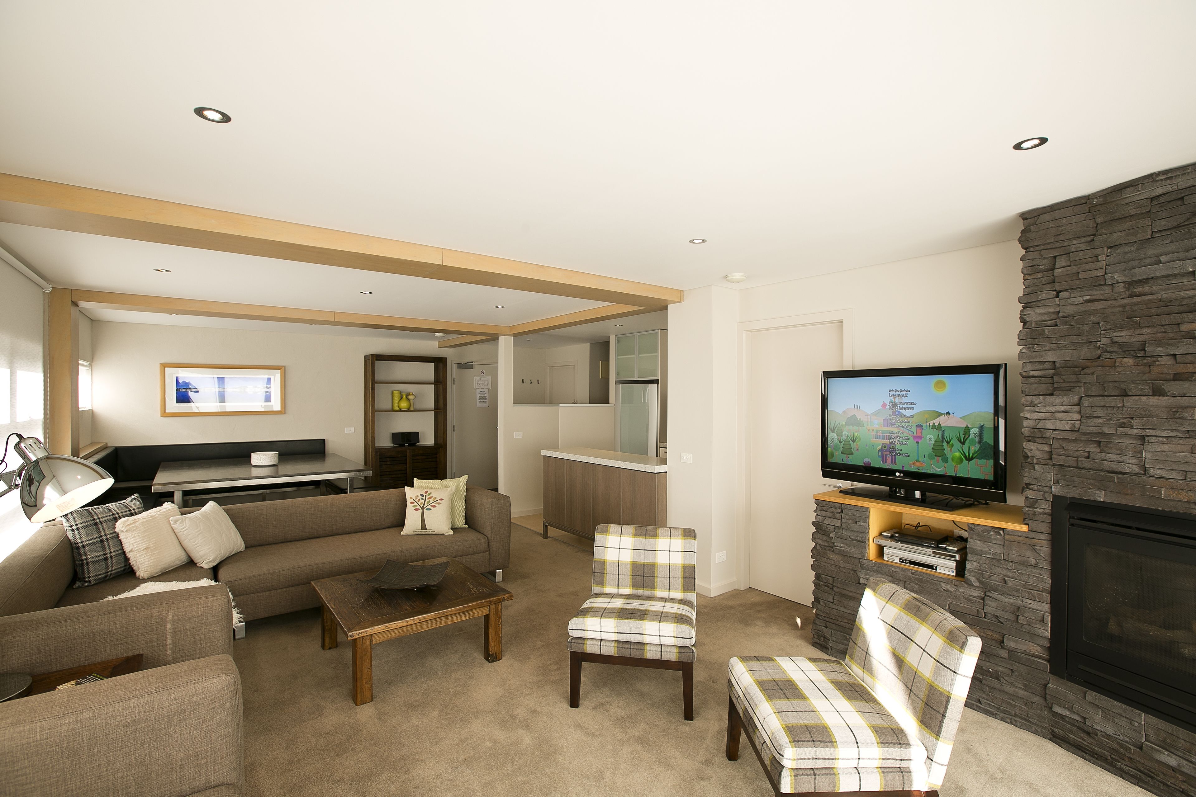 A modern living room with a sofa, armchairs, a coffee table, a TV, and a fireplace.