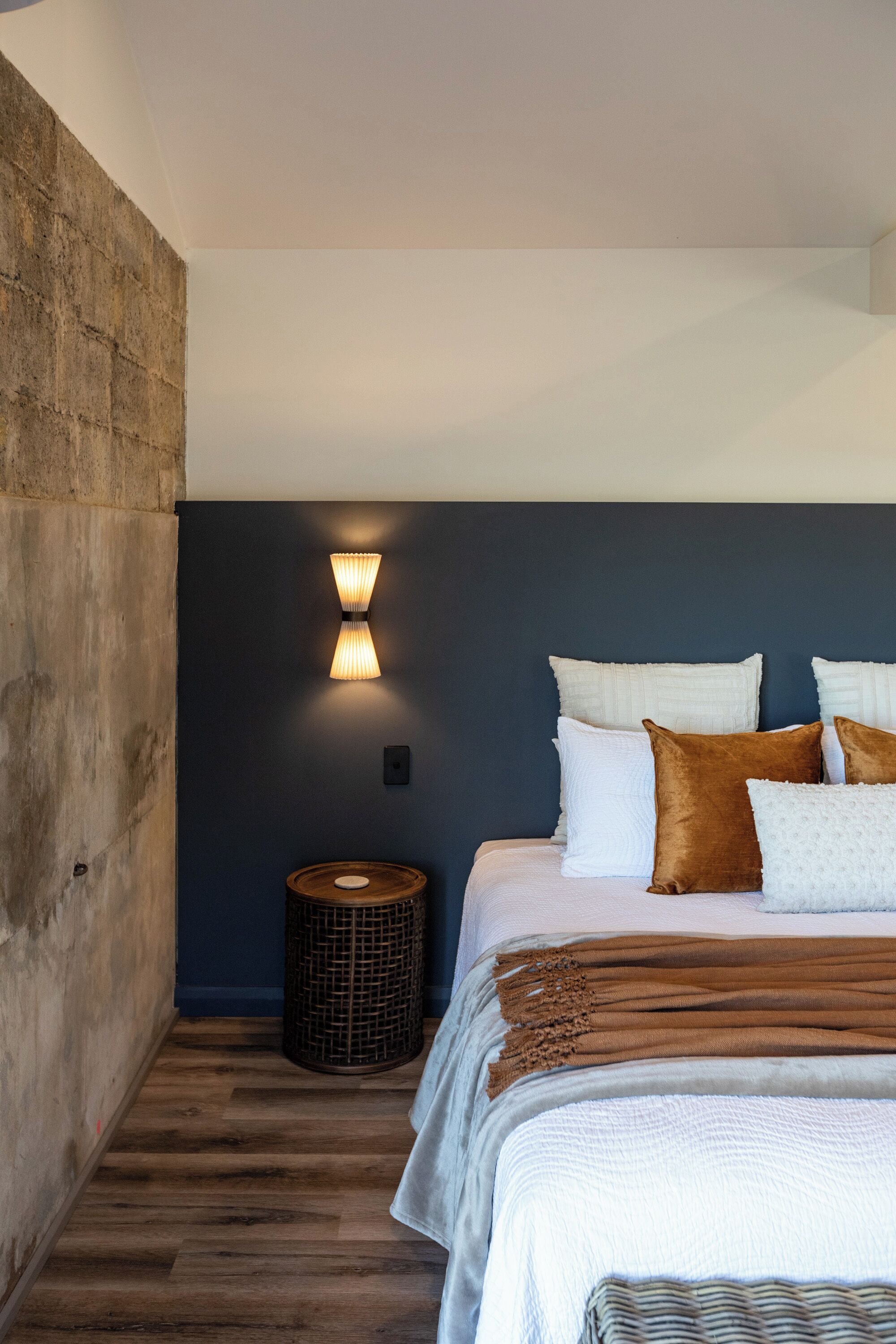 A bedroom with a large bed, dark walls, and a wooden floor.