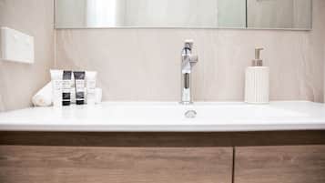 A bathroom with a white sink, a mirror, and toiletries on the counter.