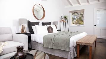 Een moderne slaapkamer met een bed, nachtkastjes, een hangplant en een raam met uitzicht.