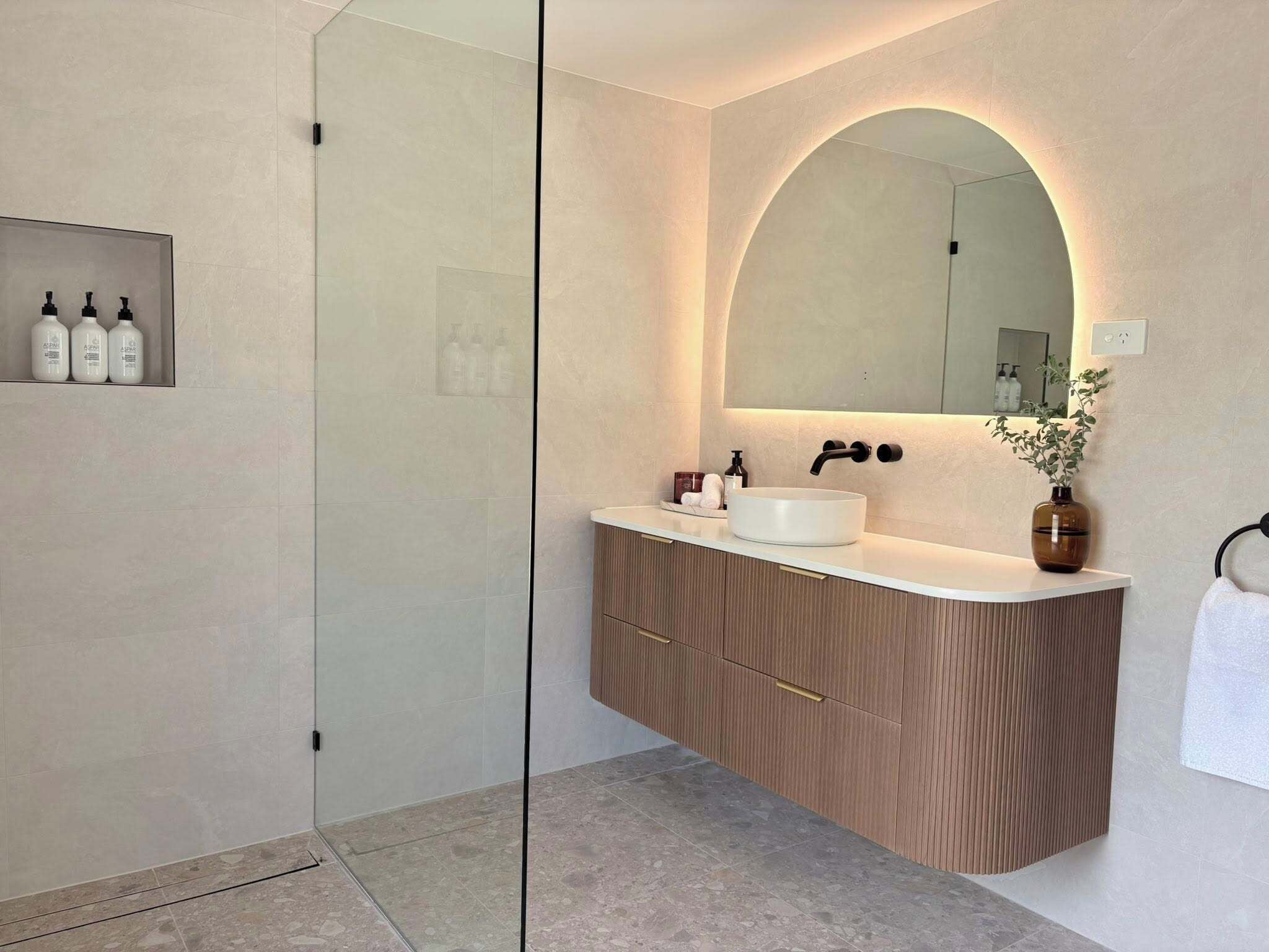 A modern bathroom with a freestanding sink, a large mirror, and a glass shower enclosure.