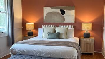 A bedroom with a bed, two bedside tables, a ceiling fan, and a window with curtains.
