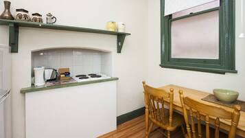 A kitchen with a white countertop, a stove, and a wooden dining table with chairs.