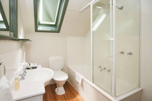 A bathroom with a toilet, sink, and glass-enclosed shower.