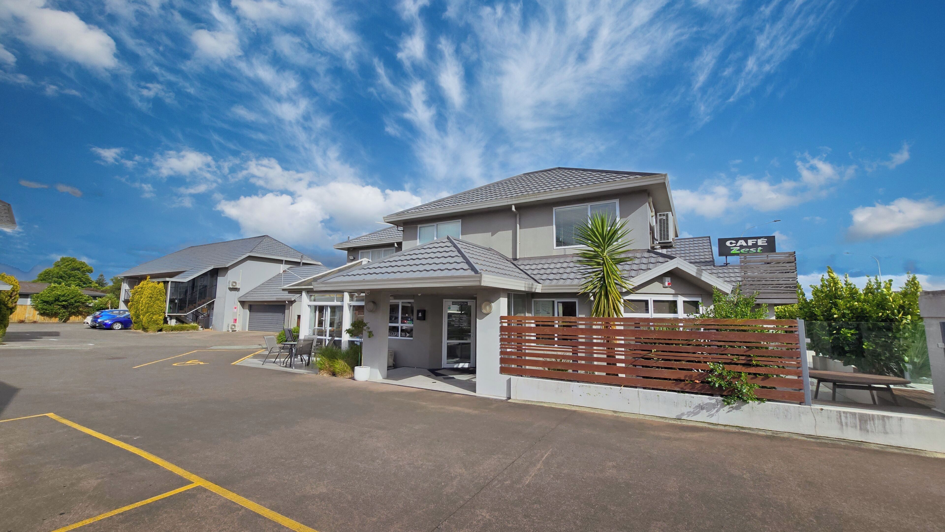 A hotel with a parking lot, a cafe, and a small outdoor seating area.