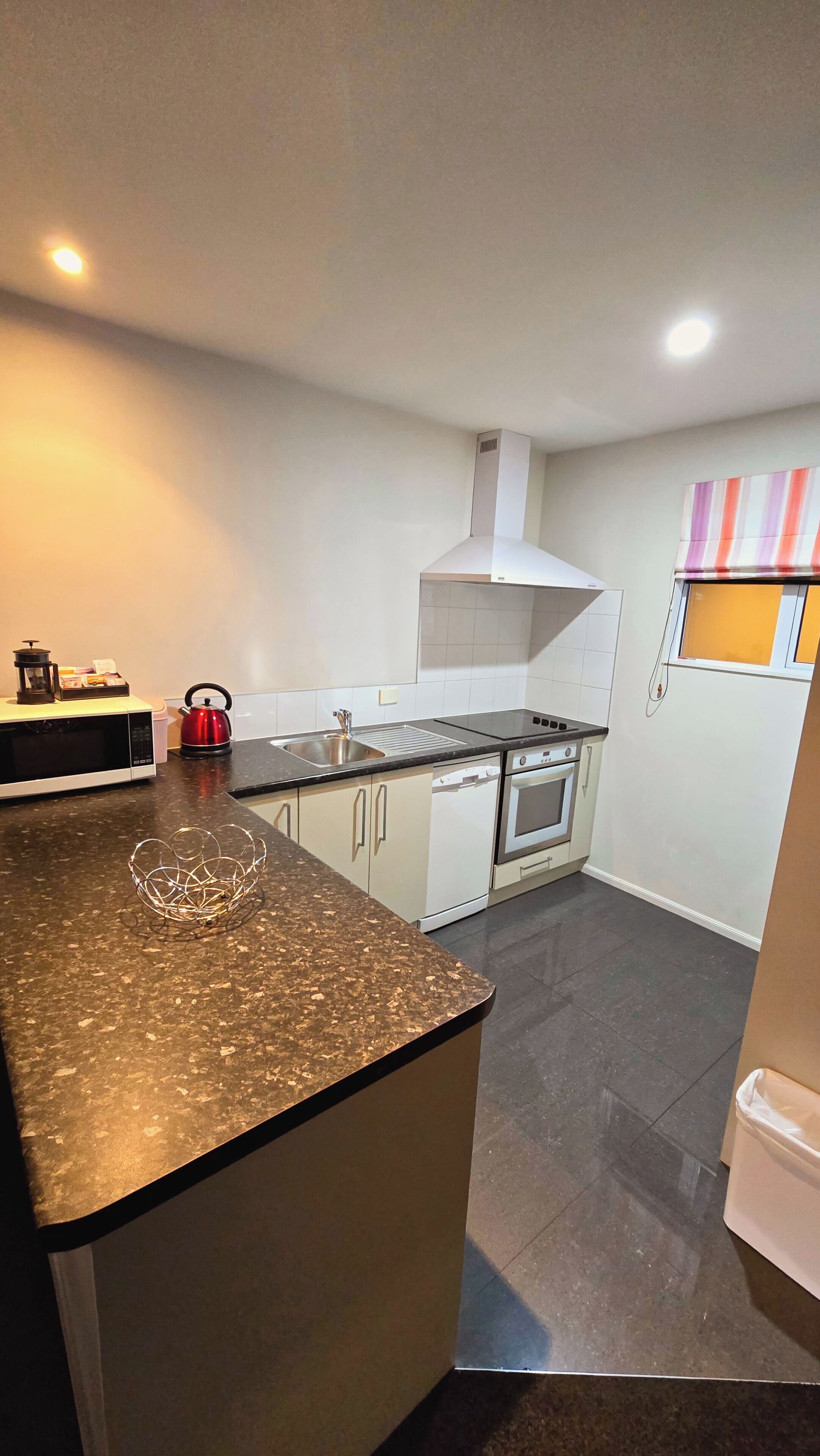 A compact kitchen with a microwave, kettle, and stove.