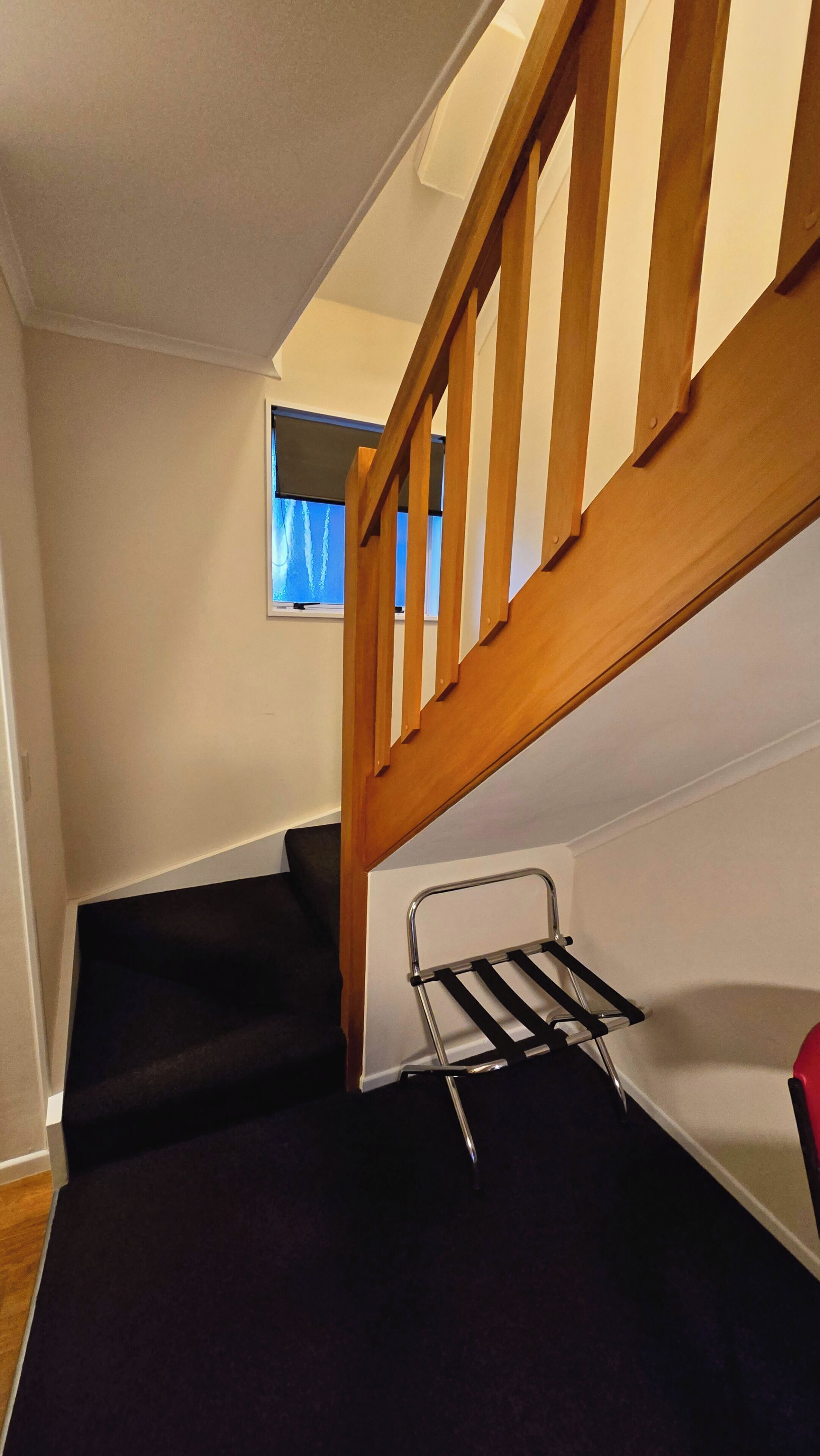 A staircase with wooden railings leading to a landing. A metal drying rack is placed on the landing.