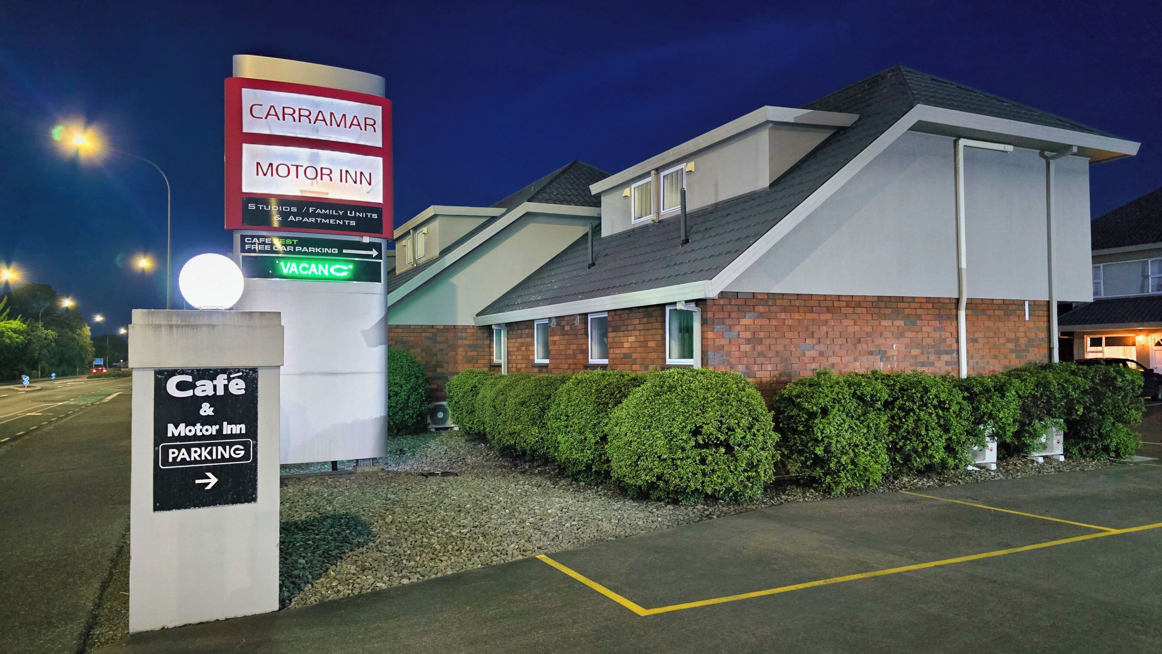 Carramar Motor Inn met een bord waarop gratis parkeergelegenheid en een café staan aangegeven.