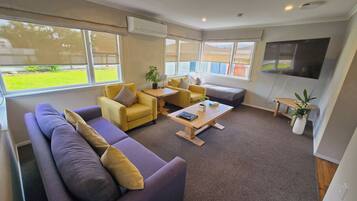 A modern living room with a sectional sofa, yellow armchairs, a coffee table, and a TV mounted on the wall.