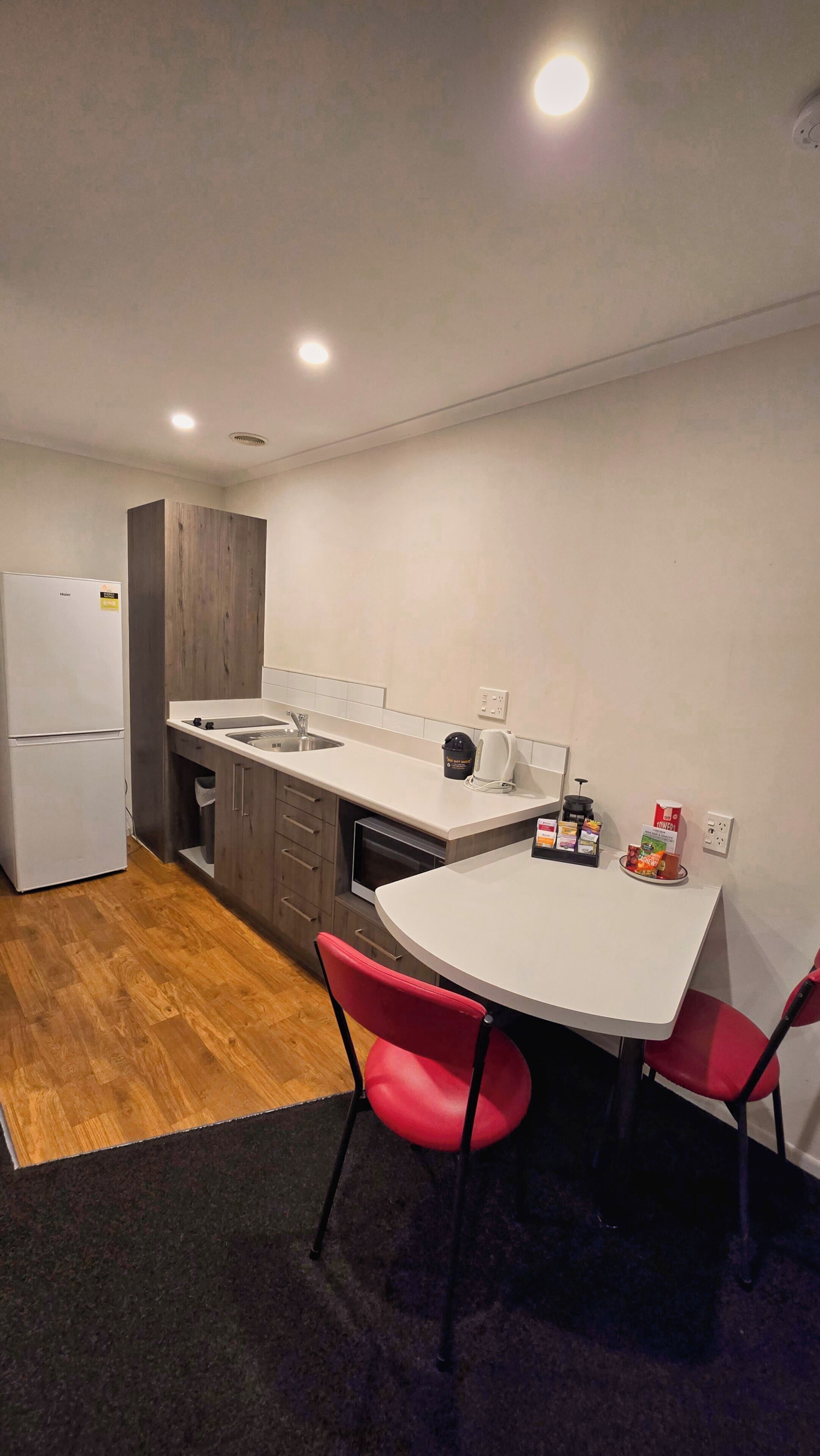 A compact kitchen with a refrigerator, sink, and a small dining table with two chairs.