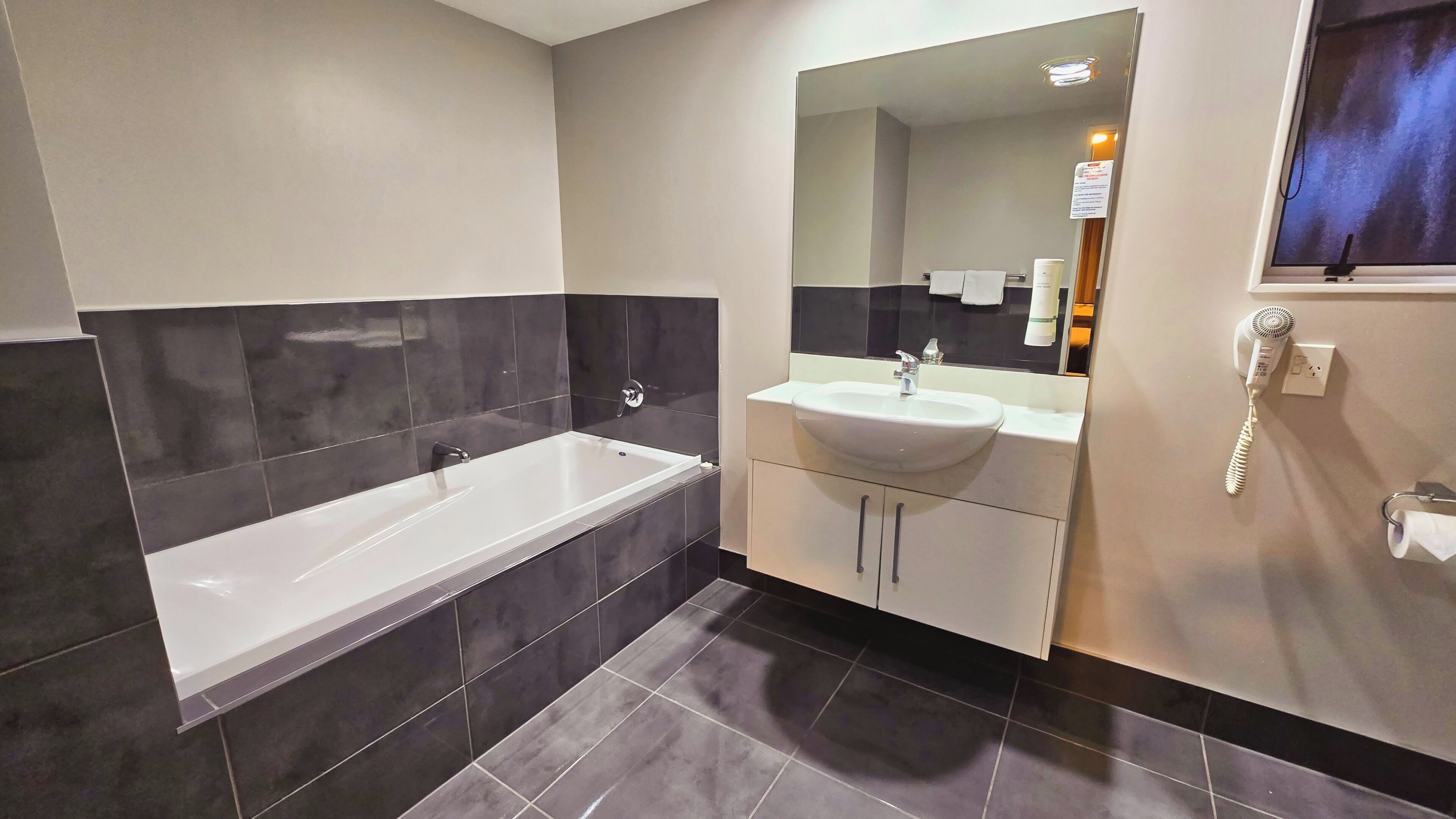 A modern bathroom with a bathtub, a sink, and a mirror.