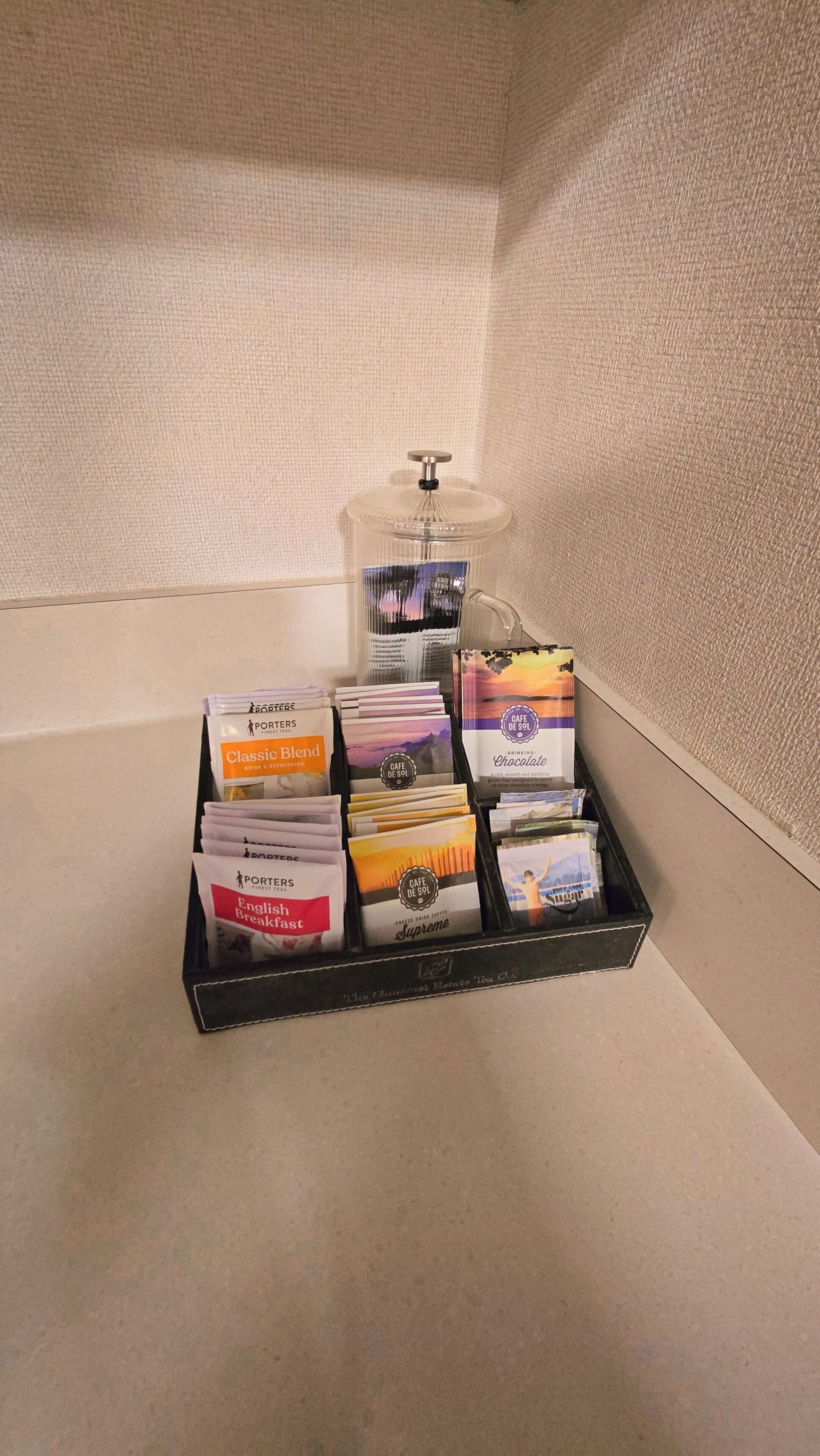 A tray of coffee and tea bags on a textured surface.