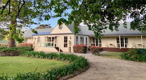 A two-story building with a covered porch and a gravel driveway. - Glen Isla House (Cowes)