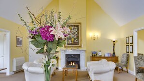 A living room with a fireplace, white furniture, and a floral arrangement on a table. - Glen Isla House (Cowes)
