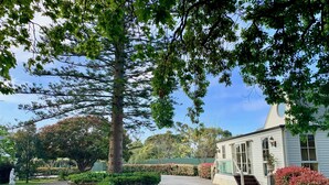 A house with a gravel driveway, a stone wall, and a well-maintained garden with various plants and a statue. - Glen Isla House (Cowes)