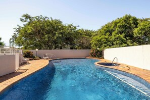 A swimming pool with a tiled edge, a small hot tub, and lounge chairs. - Kirribilli Riverfront Apartments (New Farm)