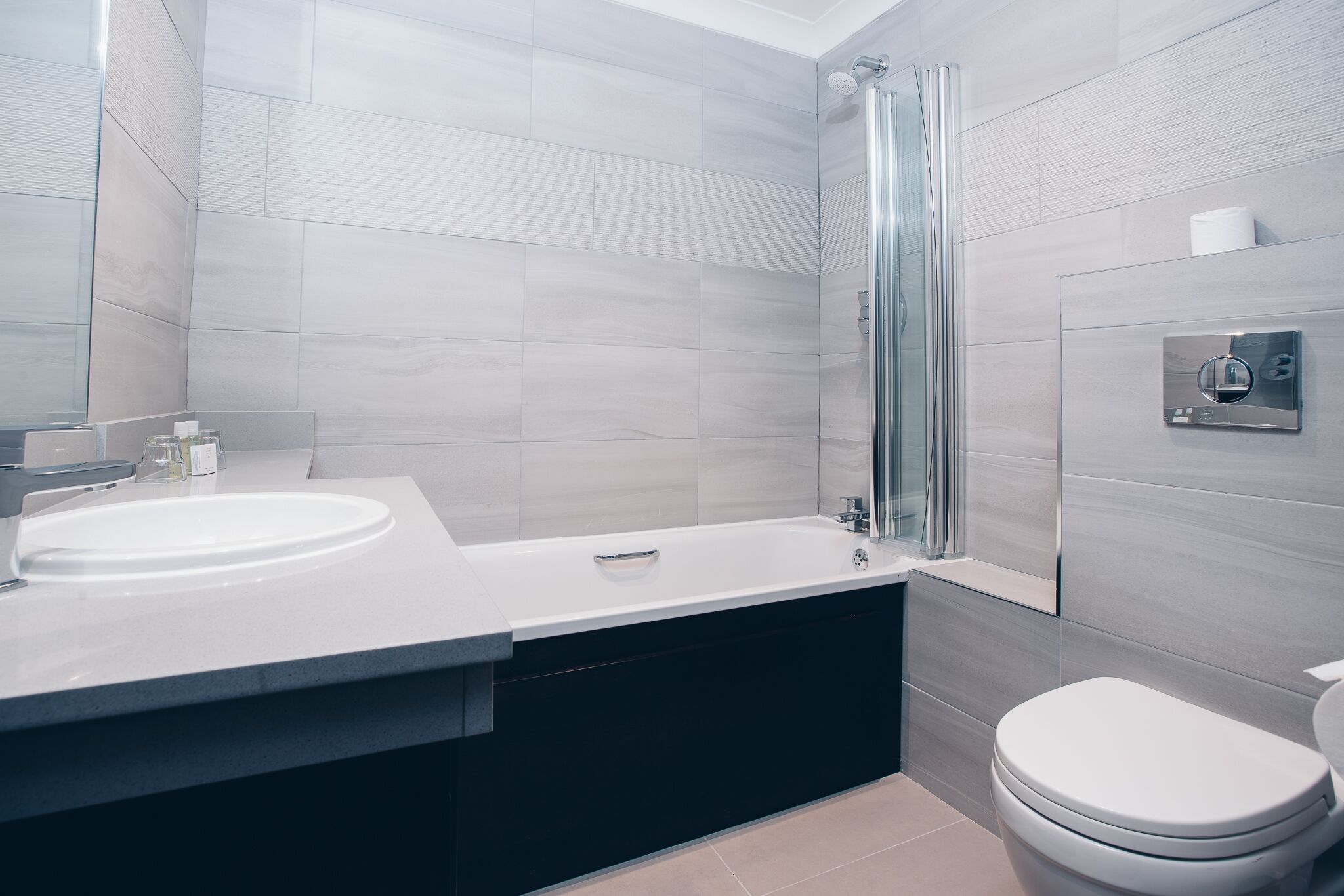 A modern bathroom with a large sink, a bathtub, and a toilet.