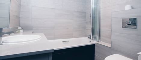 A modern bathroom with a large sink, a bathtub, and a toilet.