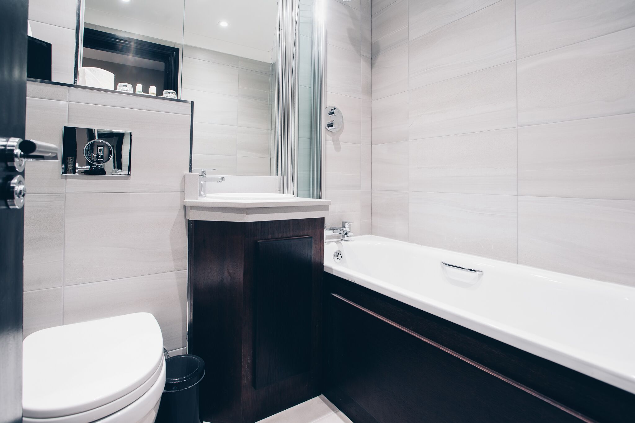 A modern bathroom with a white toilet, a sink, and a bathtub.