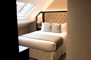 Ein Schlafzimmer mit einem großen Bett, einem gepolsterten Kopfteil und einem Oberlicht.